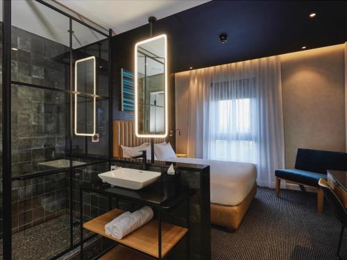 a hotel room with a bathroom with a bed and a sink at Century City Hotel Bridgewater in Cape Town