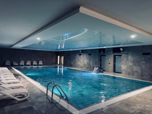 a large swimming pool with chairs in a building at Kapitańska Przystań - basen & sauna & jacuzzi & klimatyzacja & garaż in Dziwnów