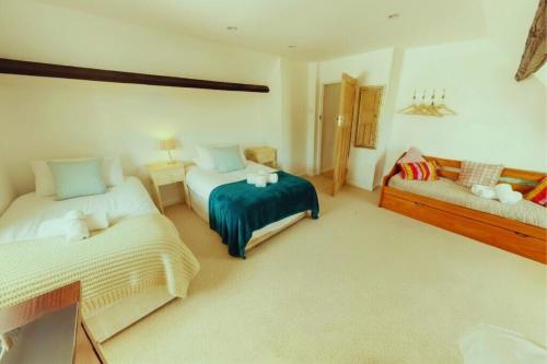 a bedroom with two beds and a couch in it at CROYDE HALLGREIN 4 Bedrooms in Croyde