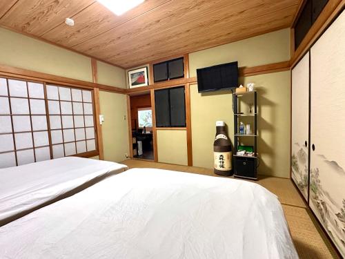 a bedroom with a white bed and a tv at Gen-en Private Hideaway Villa, Izu Forest in Izu