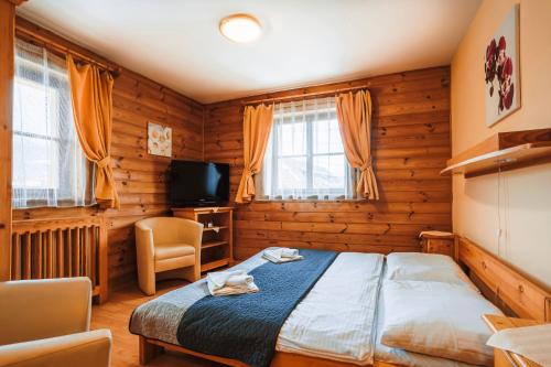 a bedroom with a bed and a tv and windows at Penzion UNA in Liptovský Ján