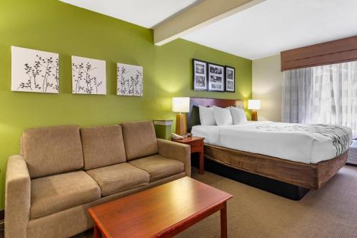 a hotel room with a bed and a couch at Sleep Inn & Suites Stockbridge Atlanta South in Stockbridge