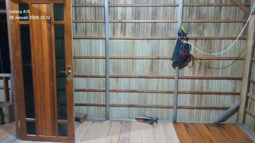 a room with a wooden wall with a pole and a door at Homestay Yenkop in Poelau Mansoear