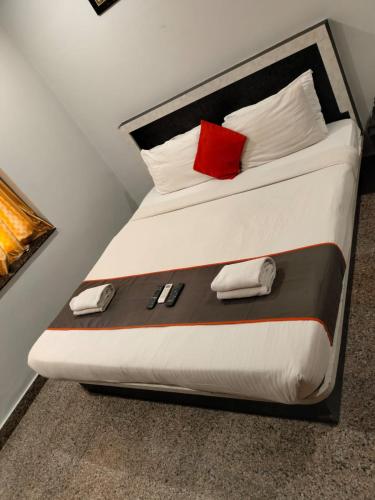 a bed with a red pillow and two phones on it at Hotel Vaishnavi in Hyderabad