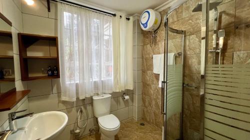 a bathroom with a toilet and a sink and a shower at Iwandaa Boutique Hotel in Nkoanrua