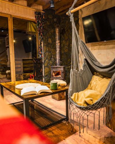 a hammock in a room with a table and a book at Bieszczadzka Hawira - Domki w Centrum przy Jeziorze z Widokiem dla Rodzin in Polańczyk