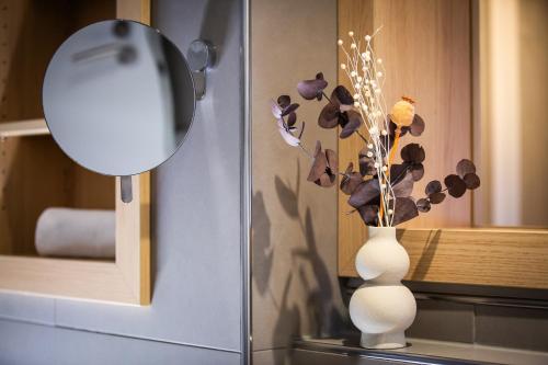 a white vase with flowers in it next to a mirror at Bude54 in Sankt Peter-Ording