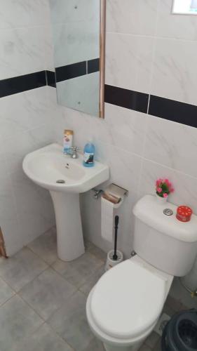 a bathroom with a white toilet and a sink at Naivera Membly Star Heights in Ruiru