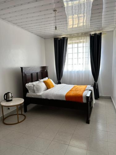 a bedroom with a large bed with black curtains at Rhacky Homes - Near JKIA & SGR in Nairobi