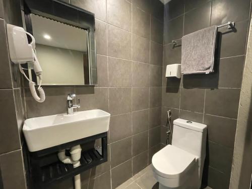 a bathroom with a sink and a toilet and a mirror at Mini Urban Guest House in Kampong Pasang