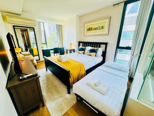 a small room with two beds and a television at Cozy Spacious 1BR 3pax GardenView, 700m BTS ThongLo, Samitivej, SKV49, Fast wifi in Bangkok