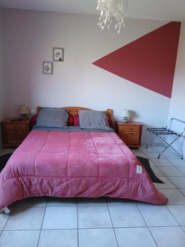 a bedroom with a large bed with a pink blanket at Les Haies Vives in Choisy