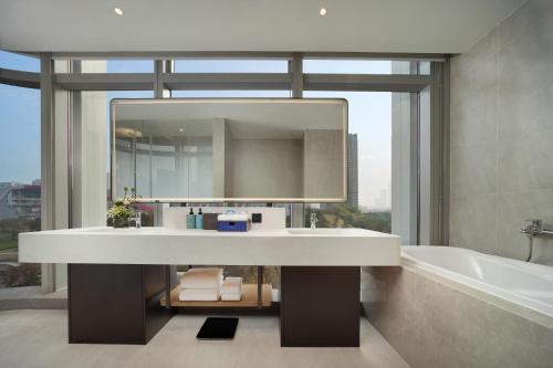 a bathroom with a sink and a tub and a mirror at Novotel Chengdu Lige in Chengdu