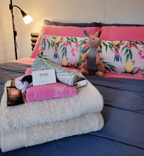 a bed with a pile of towels and a stuffed animal at The Peppercorn Shack in Kingscote