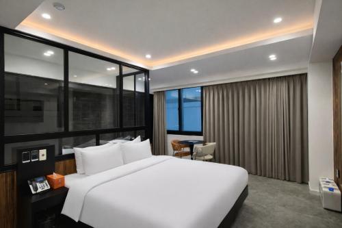 a bedroom with a large white bed and large windows at Haeundae HaeRium Hotel in Busan