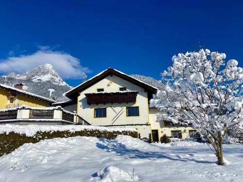 a snow covered house with a tree in front of it at Haus Thomas in Werfenweng