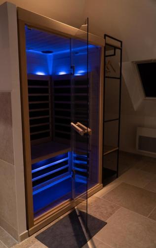 a glass shower with blue lights in a bathroom at Love Room Evasion Jacuzzi Sauna Hamamm in Saint-Cyr-sur-Loire