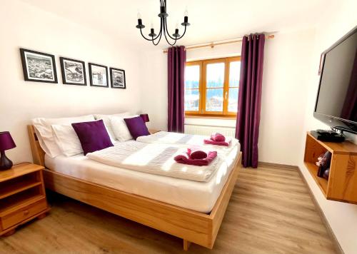 a bedroom with a large bed with purple pillows and a television at Haus Thomas in Werfenweng