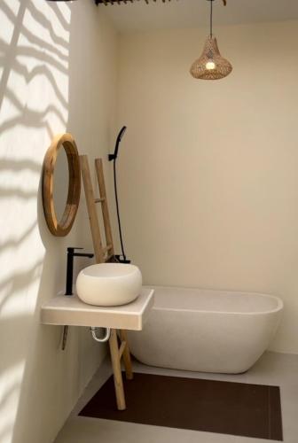 a bathroom with a white tub and a wooden chair at Sampai Villa Kama in Ngaglik