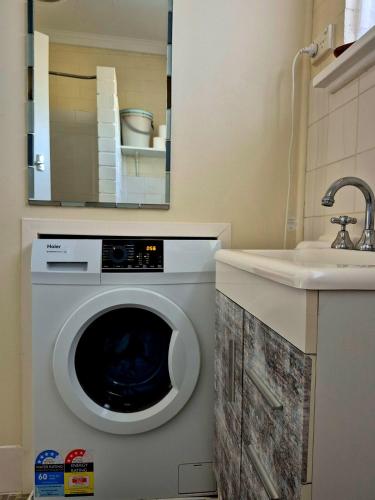 a washing machine in a bathroom next to a sink at Brownlow Beach Shack in Kingscote