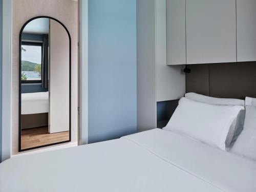 a bedroom with a white bed and a mirror at Amadria Exclusive Beach Villa in Šibenik