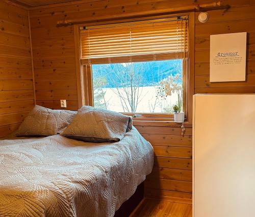 a bed in a wooden room with a window at Look at this view! 3 BR house overlooking Hardangerfjorden in Kvam