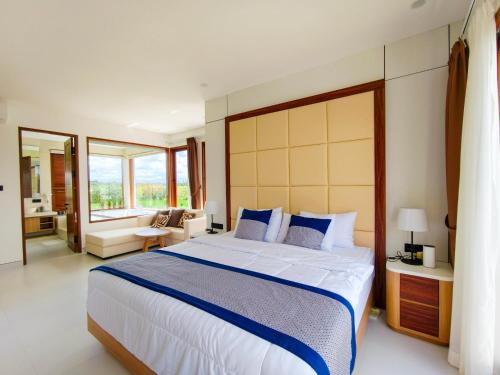 a bedroom with a large bed and a living room at Mountain Sunshine Private Villa in Darmasaba