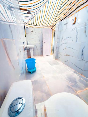 a bathroom with a toilet and a blue bucket at Jaisalmer Villa Resort & Camp Jaisalmer in Jaisalmer