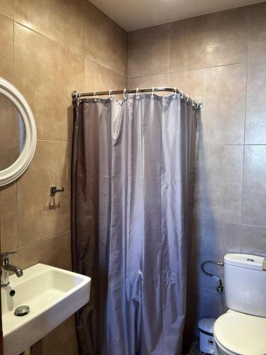 a bathroom with a shower curtain and a sink at BlackBeach village in Perissa
