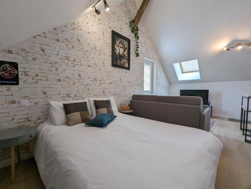 a bedroom with a large bed and a brick wall at Le Studio Neo-Retro in Digoin