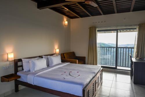 a bedroom with a large bed and a balcony at Abad Silver Mist in Vagamon