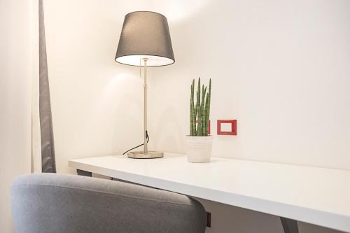 a white desk with a lamp and a cactus at Excelsior in Piombino