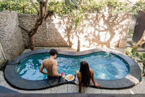 a man and a woman sitting in a swimming pool at Yoki's Bungalows in Kuta Lombok