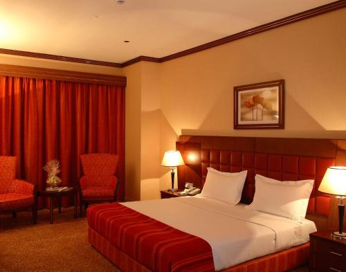 a hotel room with a bed and two chairs at Grand Central Hotel in Dubai