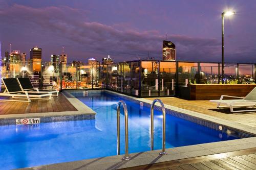 a swimming pool on top of a building with a city skyline at Soda Apartments by CLLIX in Brisbane