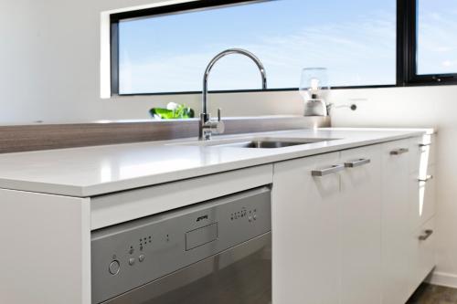 a white kitchen with a sink and a window at Soda Apartments by CLLIX in Brisbane