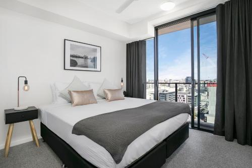 a bedroom with a large bed and a large window at Soda Apartments by CLLIX in Brisbane