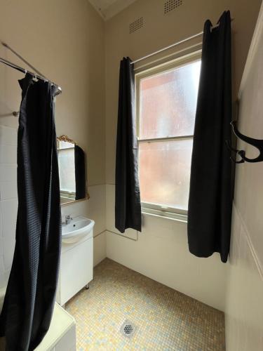 ein Badezimmer mit Toilette und einem Fenster mit schwarzen Vorhängen in der Unterkunft Junee Hotel in Junee