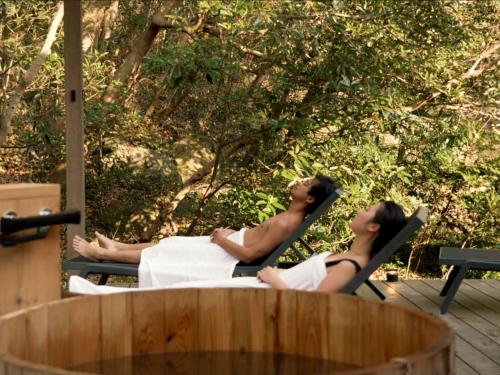 two people sitting in lawn chairs on a deck at Tiny Base in Kawazu