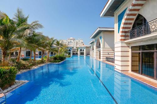 a swimming pool in a resort with palm trees at Zabeel Saray Royal Residences Lagoon Villa in Dubai