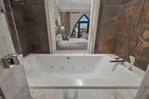 a white tub in a bathroom with a mirror at Zabeel Saray Royal Residences Lagoon Villa in Dubai