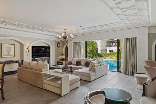 a living room with white furniture and a pool at Zabeel Saray Royal Residences Lagoon Villa in Dubai