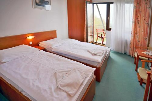 a hotel room with two beds and a window at Hotel SOREA HUTNÍK in Vysoké Tatry
