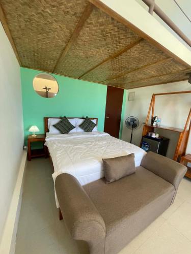 a bedroom with a large bed and a couch at Alfa Beachfront Lofts in El Nido