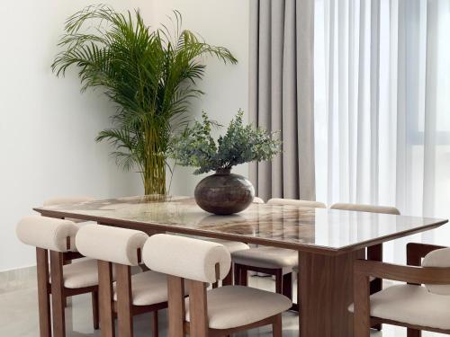 a dining room table and chairs with a plant on it at Serenity Stay - Boutique Guesthouse in Abu Dhabi