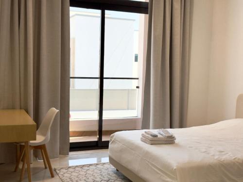 a bedroom with a bed and a desk and a window at Serenity Stay - Boutique Guesthouse in Abu Dhabi