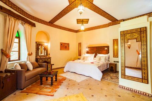 a bedroom with a bed and a couch and a mirror at Riad Lamane in Zagora