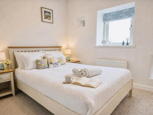 a bedroom with a bed with two books and a window at Pastures Barn in Leek