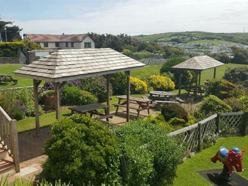a garden with picnic tables and umbrellas at Widemouth Manor Hotel in Bude