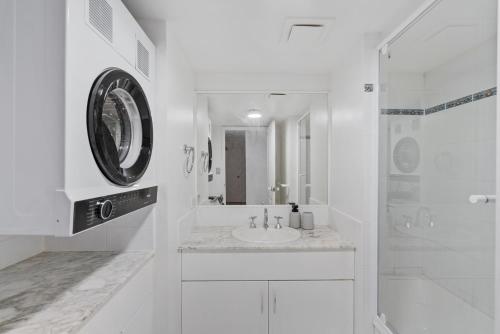 a white bathroom with a sink and a shower at Little Cove Currumbin in Gold Coast